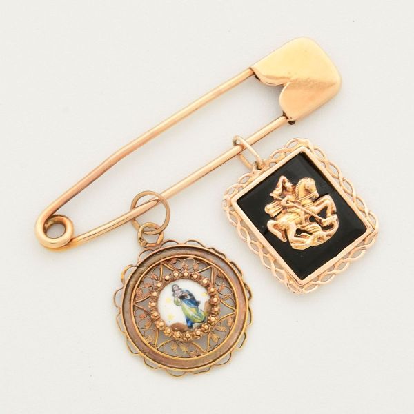 Alfinete com dois pendentes, em ouro amarelo 18 k, representando São Jorge (com trincado no ônix, na parte de trás) e N. Sra. da Conceição. Medida do alfinete 45 mm. Peso total 5,8 g.
