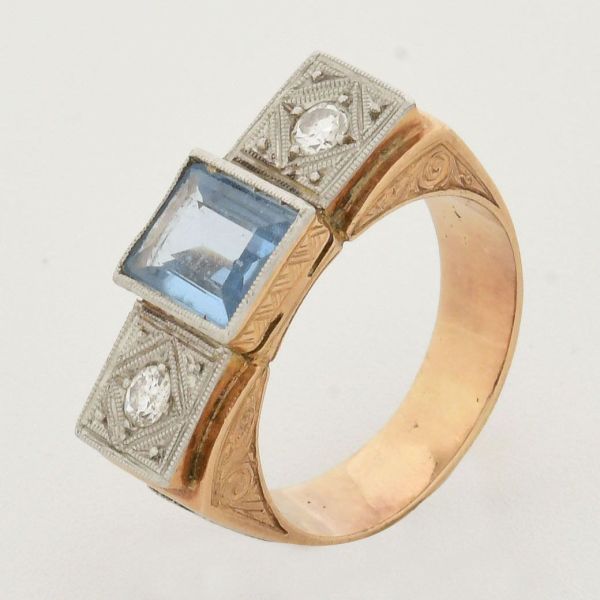 Anel em ouro amarelo 18 k, estilo art decó, com pedra central retangular de água marinha, de aprox 1,5 ct, ladeada com dois diamantes de aprox 0,03 ct cada. Aro 13. Peso total 9,3 g.