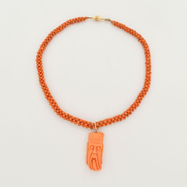 Colar em esferas de corais, medindo aproximadamente 42,0 cm e pendente igualmente em coral, em formato de sábio. Fecho e pega do pendente em ouro amarelo 18 k. Peso total 40,2 g.