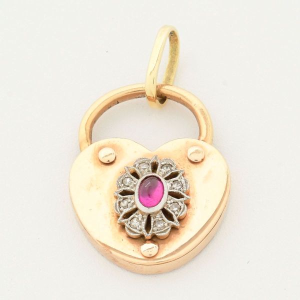 Pendente em ouro amarelo 18 k, em formato de coração, com medalhão decorado com rubi ceentral, circundado com pequenos diamantes. Medida 3,0 x 2,0 cm. Peso 7,0 g.