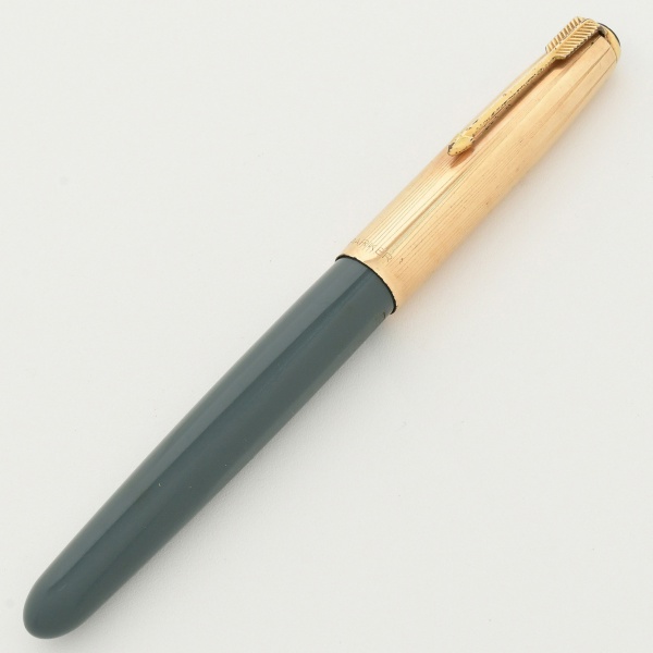 PARKER 51 - Caneta tinteiro, corpo em resina preciosa na cor cinza, tampa dourada e aneleira prateada. Apresenta inscrição personalizada, ilegível no corpo.