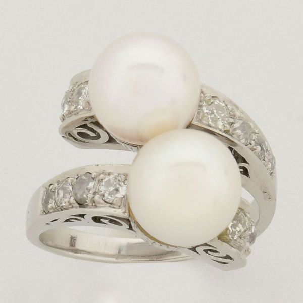 Anel em ouro branco, tendo em sua parte principal, duas pérolas de aproximadamente 8 mm cada, ladeadas com pequenos diamantes. Aro 12. Peso total 10,4 g.