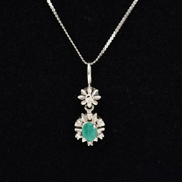 Colar em ouro branco e pingente em formato floral, com esmeralda central circundada com pequenos diamantes. Comprimento aprox 49,5 cm. Peso total 3,9 g.