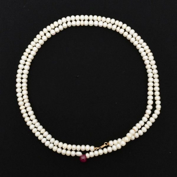 Colar de uma volta com pérolas tendo na parte central um rubi como pendente. Comprimento aprox 87,0 cm. Fecho em ouro amarelo 18 k. Peso total 43,4 g.