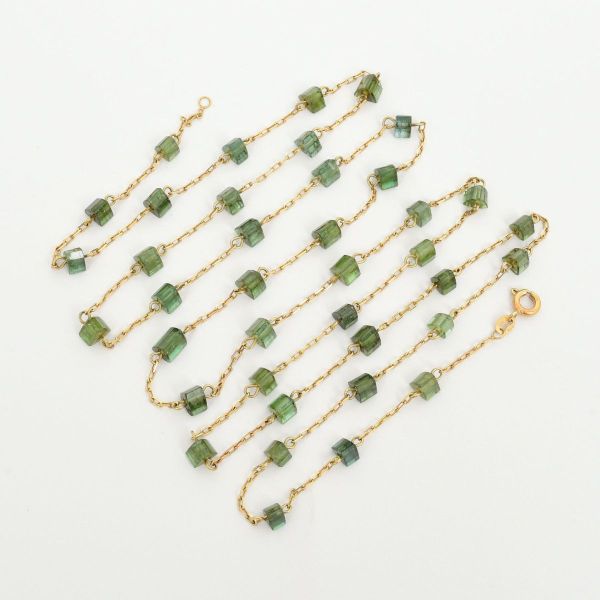 Colar em ouro amarelo 18 k 750, corrente em mini elos, intercalados com pedras verdes em formato triangular. Comprimento aproximado 86,0 cm. Peso total 11,8 g.