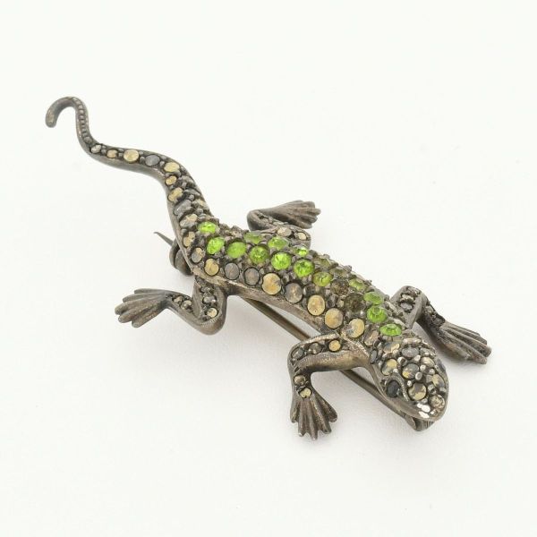 Broche em prata 935, contrastado, em formato de salamandra, decorado com pedras verdes (ausência de algumas). Comprimento 6,3 cm. Peso total 15,4 g.