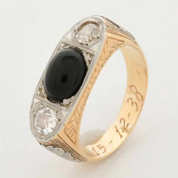 Anel em ouro amarelo 18 k, com ônix central, medindo 7,5 x 6, x 3,5 de 1,0 ct e dois diamantes de aprox. 0,20 ct cada. Aro 15. Peso total 7,2 g.