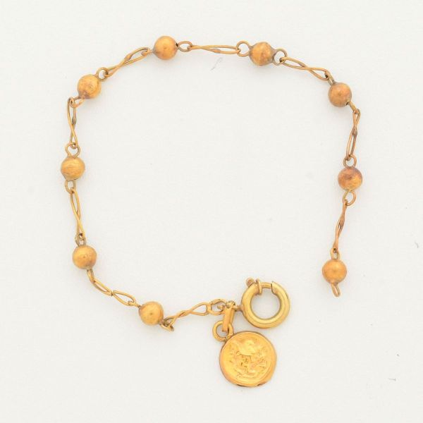 Pulseira infantil, em ouro amarelo 18 k, modelo terço, com mini pendente sacro em ouro amarelo 18 k. Comprimento 11,5 cm. Peso total 1,0 g.