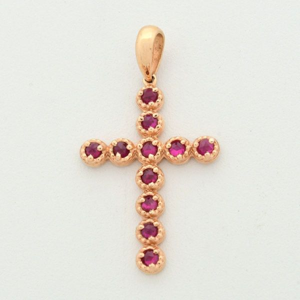 Pendente em ouro amarelo 18 k, em formato de cruz, cravejado com 11 rubis, medindo 3,0 x 1,2 cm, Peso total 2,5 g.