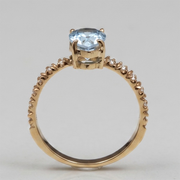 Anel em ouro amarelo 18 k, com doze diamantes de aproximadamente 0,01 ct cada e um topázio azui Sky Blue, lapidação gota de aprox 1,30 ct no total. Aro 18. Peso total 2,7 g.