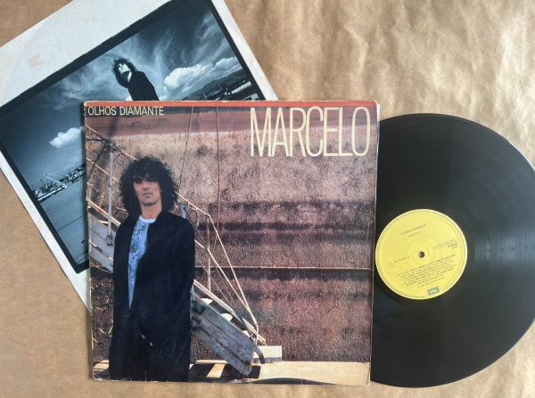 LP: Artista: Marcelo / Album: Olhos Diamante | Selo: EMI | Cód: 31C 064 422975Capa (VG -): Muito Bom: marcas superficiais, com detalhes visuais; pode conter leve rasura como um nome; leve depreciação 