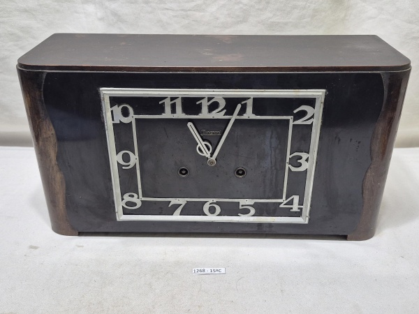Relógio de mesa antigo da marca Junghans com caixa em madeira escura, design Art Déco e mostrador retangular com numerais prateados estilizados. Medindo 39,5cm x 13,5cm x 21cm de altura, 22cm x 16cm o
