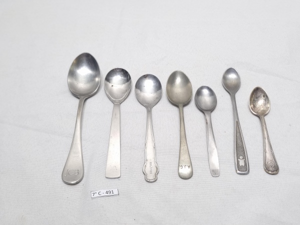 Lote de 7 talheres variados em metal, com propagandas diversas. Medindo a colher maior 17cm de comprimento.