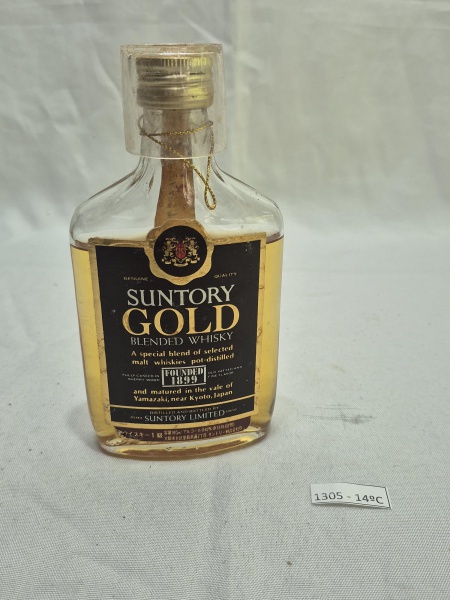 Mini garrafa do Whisky dec 70 japonês Suntory Gold acompanhado copo em plástico duro. A garrafa está lacrada, porém o liquido aparenta estar evaporado.