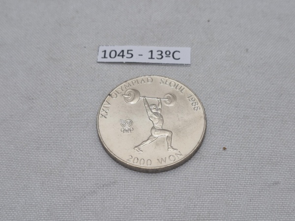 Moeda comemorativa de 2000 Won da Coreia do Sul, emitida em 1988 para os XXIV Jogos Olímpicos de Verão em Seul. Medindo 3,3cm de diâmetro.