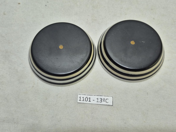 Par de becões em galalite, década de 70 nas cores preto e brando. Medindo 6,5cm de diâmetro, um deles com fio de cabelo na base.