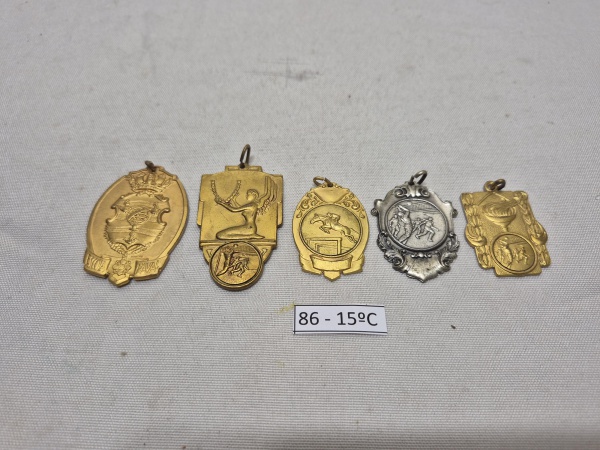 Conjunto de 5 medalhas antigas colecionáveis em metal dourado e prateado, com temática da Escola Naval e esportes diversos (hipismo, vôlei e esgrima), apresentando acabamento em relevo e argolas de su