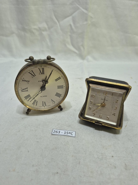 Conjunto de 2 relógios de mesa vintage, sendo um modelo despertador Endura em metal com algarismos romanos e um relógio de viagem Seth Thomas em estojo dobrável de couro preto. Medindo o maior 9cm de