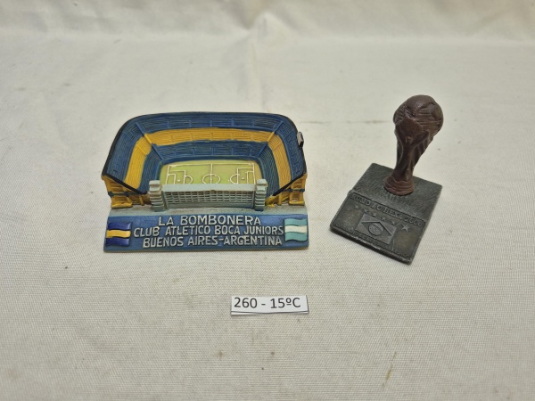 Conjunto de colecionáveis de futebol composto por miniatura tridimensional do estádio La Bombonera do Boca Juniors e réplica da taça da Copa do Mundo sobre base com a inscrição "Rumo ao Hexa 2006". Me