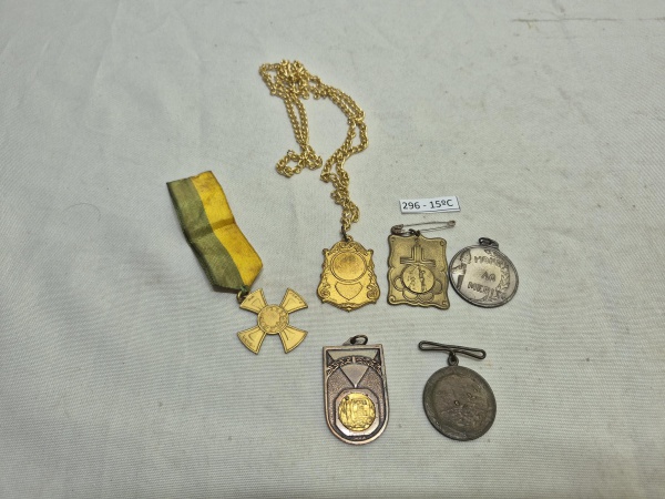 Conjunto de 6 medalhas e condecorações variadas, incluindo uma peça com corrente dourada e medalha "Honra ao Mérito" em metal prateado. Medindo a maior 4cm x 3,5cm.