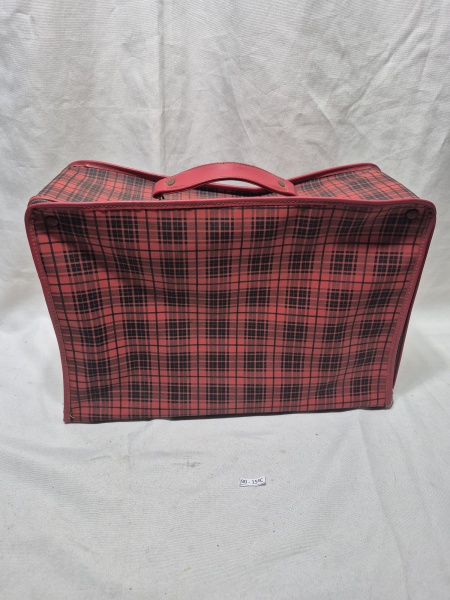 Mala de viagem antiga em material flexível com estampa xadrez em tons de vermelho e preto, apresentando fechamento por zíper periférico, alça de mão reforçada e interior forrado com sinais de uso. Med