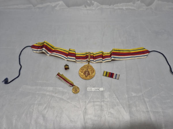Conjunto de condecoração da Justiça Militar composto por comenda de pescoço em metal dourado com fita de gorgorão listrada, miniatura, barreta e roseta de lapela correspondentes. Medindo a medalha 4cm