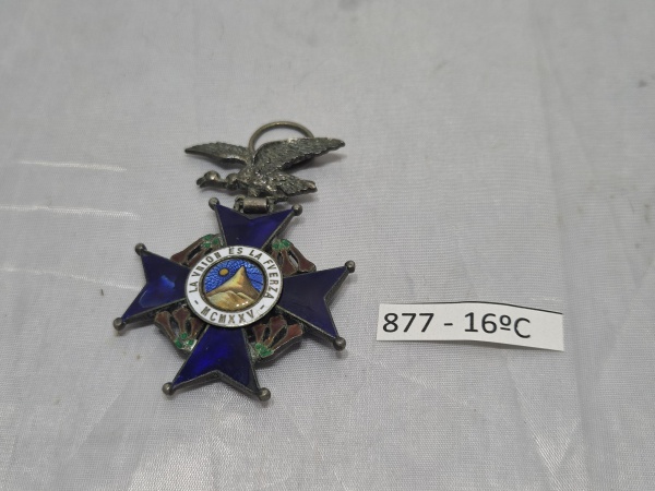 Comenda da Ordem do Condor dos Andes da Bolívia em metal prateado e esmalte azul, apresentando o lema "La Unión es la Fuerza - MCMXXV" e suspensão em formato de condor alado. Medindo 4cm x 4cm.