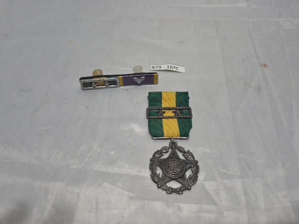 Medalha Militar de Prata por 20 anos de bons serviços das Forças Armadas do Brasil em metal prateado com fita e passadeira de duas estrelas, acompanhada de barretas compostas de lapela. Medindo 3,5cm