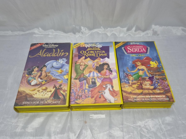 Lote composto por 03 fitas VHS originais da Disney ("Aladdin", "O Corcunda de Notre Dame" e "A Pequena Sereia - Ariel, a Babá"), em versões dubladas com estojos plásticos amarelos originais de época.