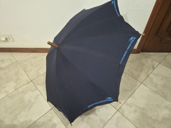 Guarda-chuva vintage na cor azul-marinho com cabo curvo e haste em madeira, personalizado com a estampa da companhia aérea Aerolíneas Argentinas. Em bom estado. Medindo 90cm de comprimento fechado, 11