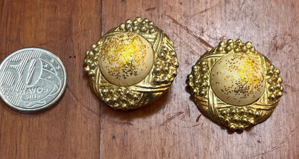 Brincos vintage de pressão (estilo botão) com base estruturada em metal dourado envelhecido e um cabochão central bege decorado com glitter dourado.