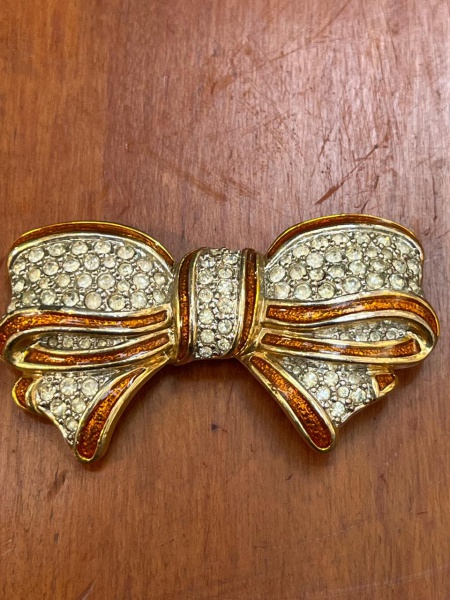 Broche vintage em formato de laço, um acessório clássico de alta chapelaria e joalheria de fantasia, popularizado principalmente entre as décadas de 1970 e 1990.