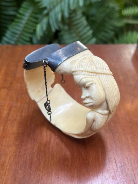 Bracelete ou bracelete articulado feito de marfim de lei entalhado, apresentando uma figura com traços fisionômicos de estilo africano.