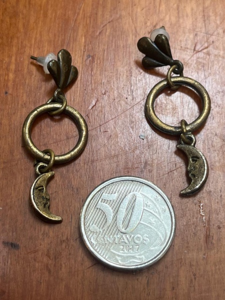 Brincos artesanais em tom bronze antigo, decorados com pingentes de meia-lua com rosto esculpido.