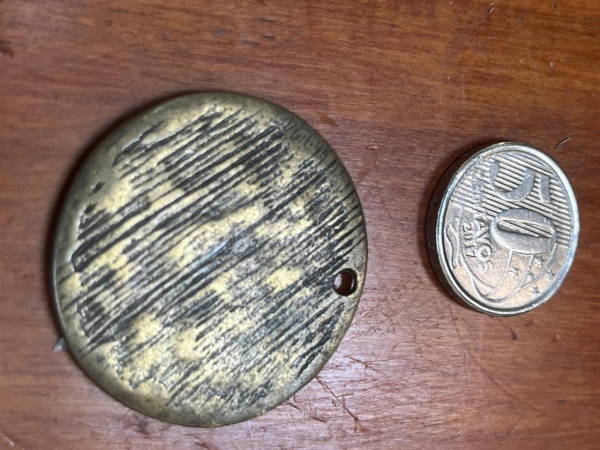 Pingente, medalha ou placa de metal envelhecido.