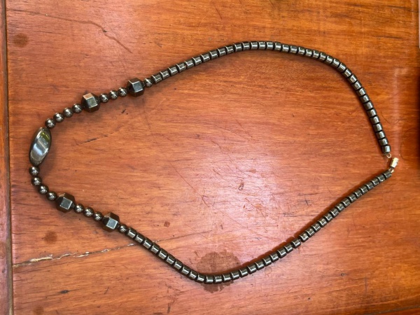 Colar de hematita, uma pedra mineral conhecida por seu brilho metálico cinza-escuro ou preto e que frequentemente possui propriedades magnéticas. 20 cm de comprimento.