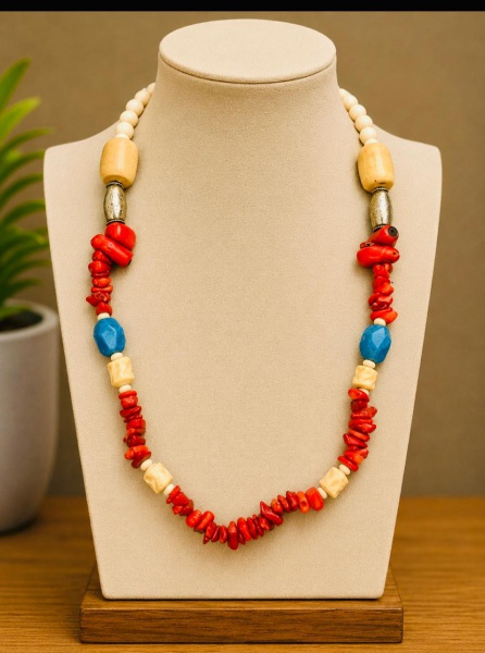 Este colar vintage é feito com contas de coral vermelho, pedras no tom azul turquesa e elementos esculpidos em marfim, acompanhados por detalhes em prata trabalhada. É uma peça artesanal e rústica que
