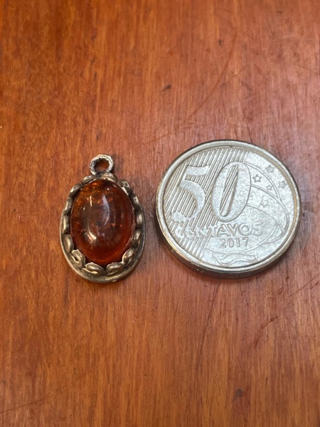 Pingente de prata envelhecida com uma gema de âmbar lapidada em formato cabochão oval.