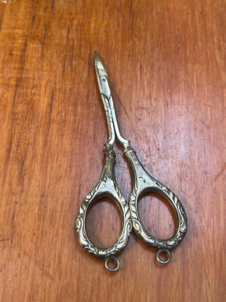 Tesourinha antiga de costura ou manicure, muito valorizada como item de coleção devido aos seus detalhes ricamente trabalhados. O cabodecorado apresenta ornamentos em relevo, estilo comum no final do