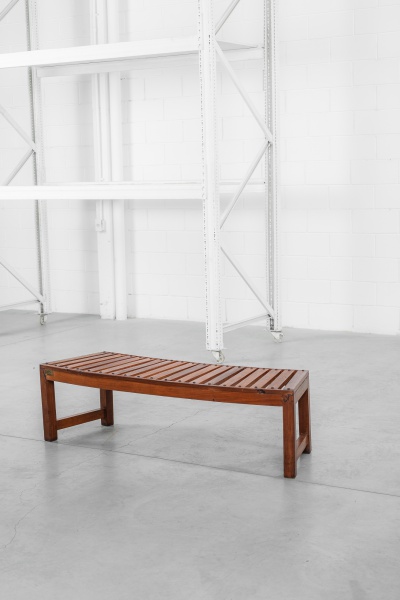 Selado banco ripado em madeira nobre com inusitado formato curso. Fabricado pela Moveis Aroeira. Apresenta sinal de restauro em um dos pés. 146 x 46 x 42cm de altura.