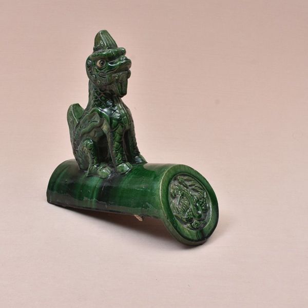 Telha ornamental chinesa representando dragão sobre cumeeira. Peça arquitetônica em cerâmica vidrada em verde-esmeralda intenso, representando dragão em posição sentada, com corpo escamado. A figura a