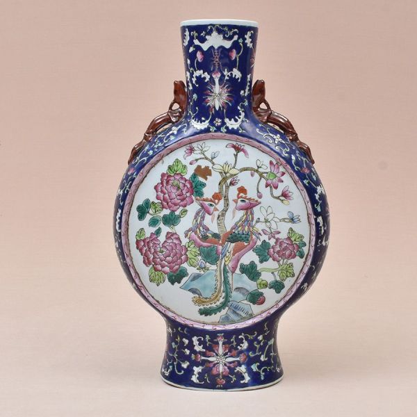 Vaso-lua (moon flask) em porcelana chinesa, decoração ao gosto família-rosa sobre fundo azul-cobalto. Peça de corpo achatado e circular, sustentada por pé evasado e gargalo cilíndrico, ladeada por dua
