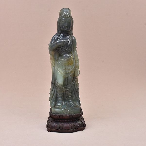 Escultura chinesa do sec. XIX em jade esculpida representando Guanyin. Escultura de vulto redondo, entalhada em bloco único de jade de tonalidade verde- com variações naturais de tom (mais escura na c
