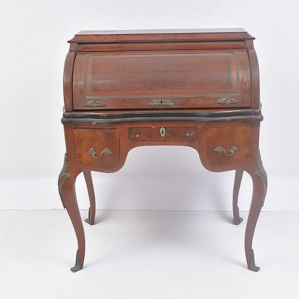 Escrivaninha francesa em estilo Louis XV, executada em madeira nobre . Estrutura sobre quatro pés cabriolé ricamente entalhados com motivos rocaille, finalizados por sabots em bronze. O tampo superior