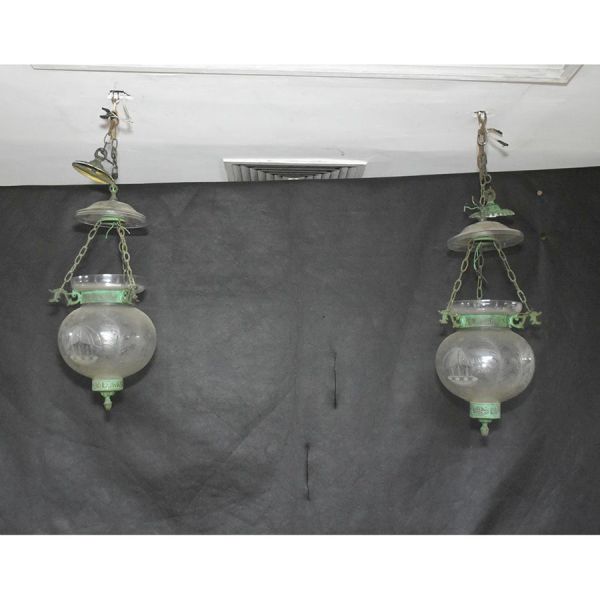 Par de lustres em cristal gravado e bronze, suspensos por correntes metálicas e compostos por globos esféricos em cristal incolor ricamente decorados com gravações florais e folhagens. Destacam-se pel
