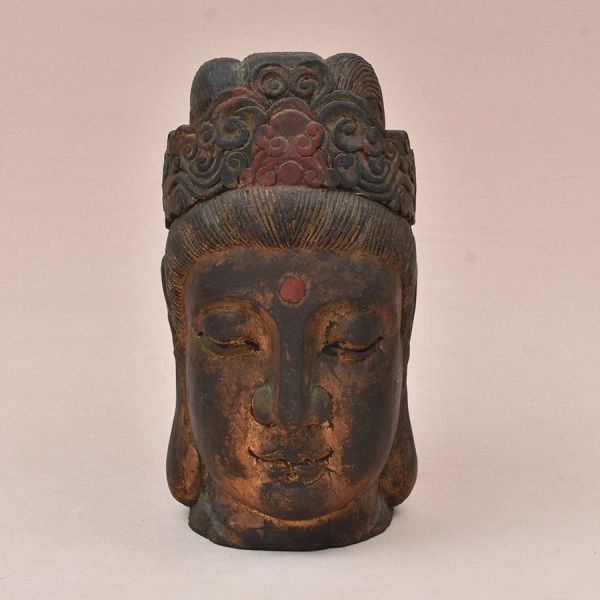 Cabeça de grande porte, esculpida em madeira maciça, representando Guanyin (ou Bodhisattva), divindade búdica em expressão de profunda serenidade meditativa — olhos semicerrados voltados para baixo, s