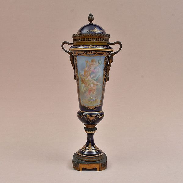 Ânfora em porcelana francesa de Sèvres, fundo azul-cobalto, com guarnições em bronze do século XIX. Corpo afunilado, tampa em cúpula perfurada com pinha de remate, alças em bronze patinado no formato