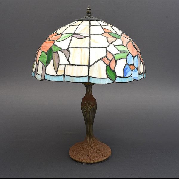 Luminária de mesa com cúpula em vitral americana estilo Tiffany. Composta por segmentos de vidro opalescente e colorido — tons de creme, verde, coral, cinza-lilás e azul, formando motivo floral estili