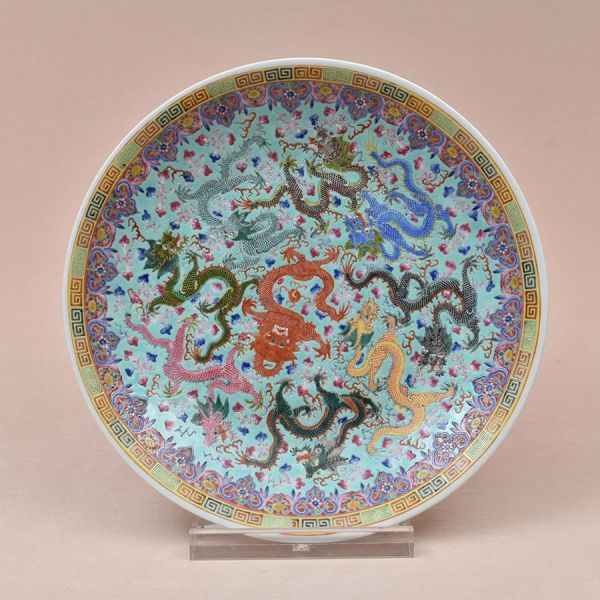 Prato chinês em porcelana esmaltada, fundo turquesa, decorado com composição de nove dragões multicoloridos (vermelho, azul, verde, amarelo, cinza, rosa, preto) entrelaçados em movimento sinuoso entre