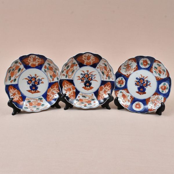 Conjunto de três pratos em porcelana Imari japonesa, de formato lobado, decorados em policromia sob e sobre o esmalte, nas tradicionais tonalidades azul-cobalto e vermelho-ferroso, com delicados detal